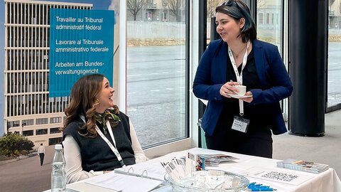 Zwei Frauen sitzen an einem Tisch und unterhalten sich mit einer dritten Frau.