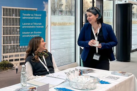 Zwei Frauen sitzen an einem Tisch und unterhalten sich mit einer dritten Frau.