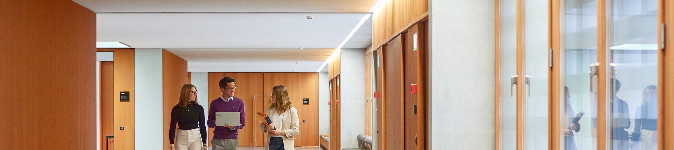 3 people walking down a corridor